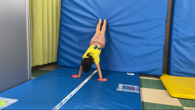マットに手をつき壁倒立をする子ども