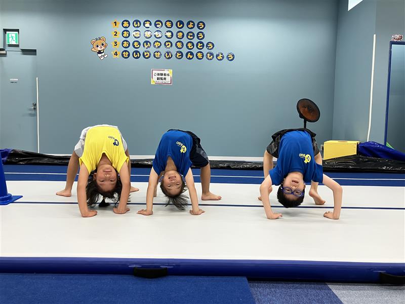 3人の子どもが並んでブリッジをしている様子