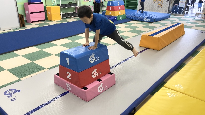 体操教室で3段の跳び箱を跳ぶ男の子の様子