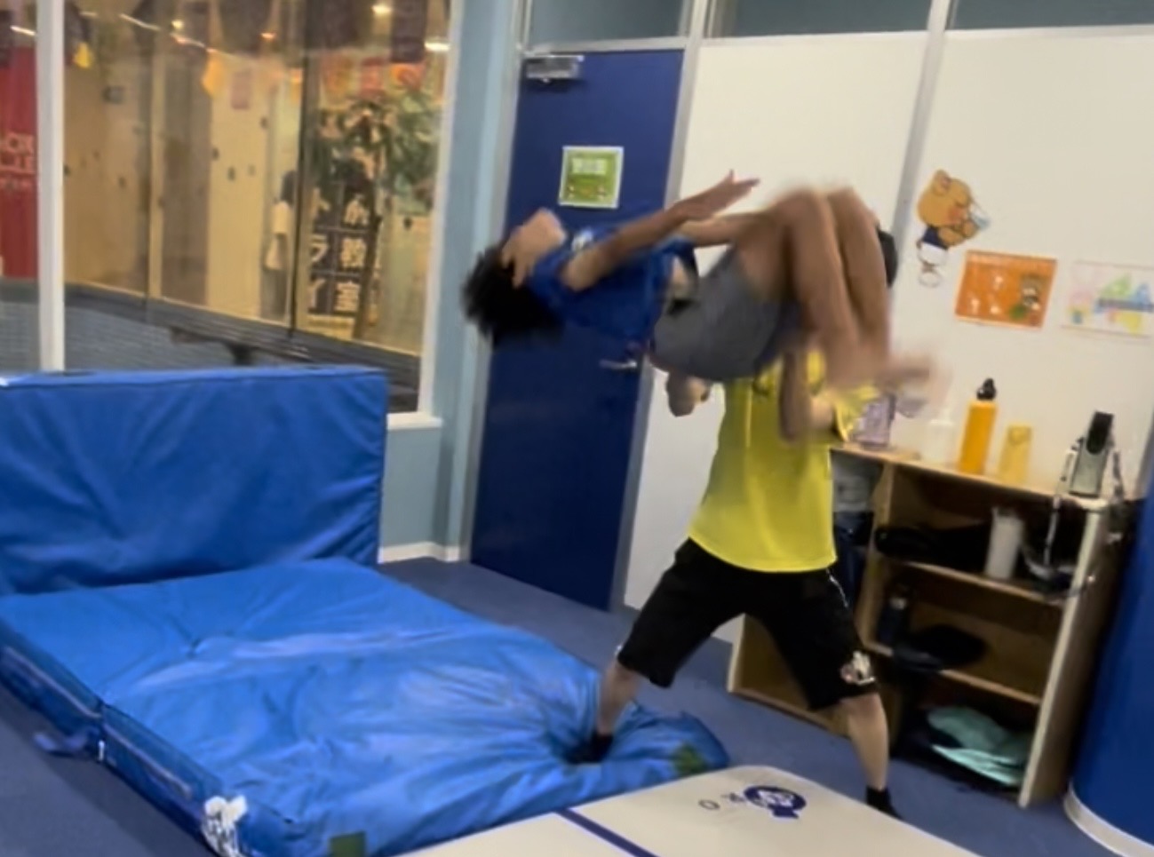 体操教室の先生に空中で補助を受けながらバク宙をする男の子の様子