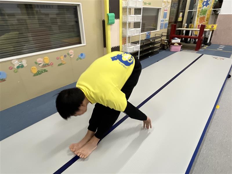 伸膝前転で回転後、膝を伸ばしたまましっかりと地面を手で押し起き上がる最後の立ち上がりの様子