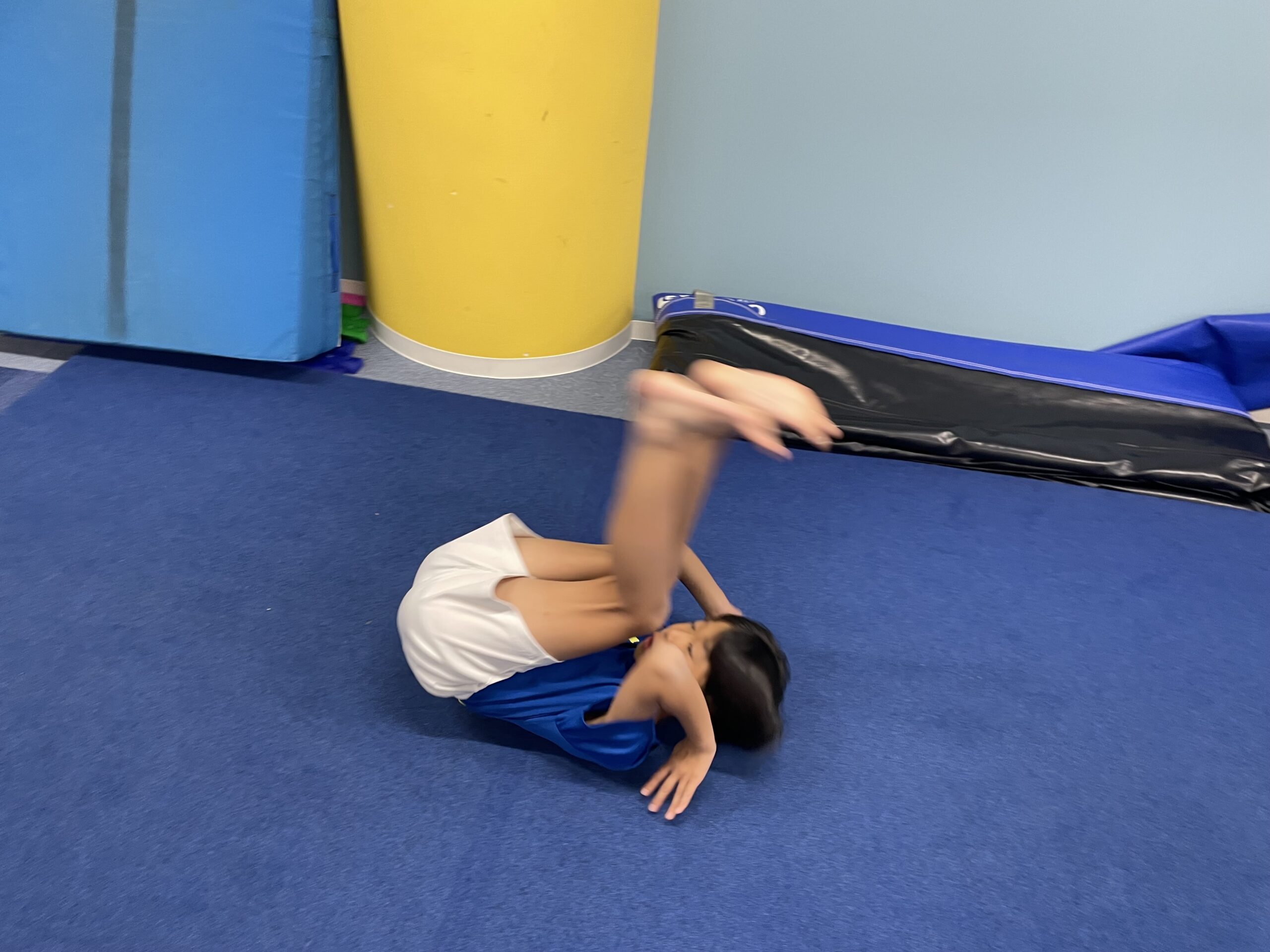 後転倒立の助走のために足を上に向け後転をしている男の子の様子
