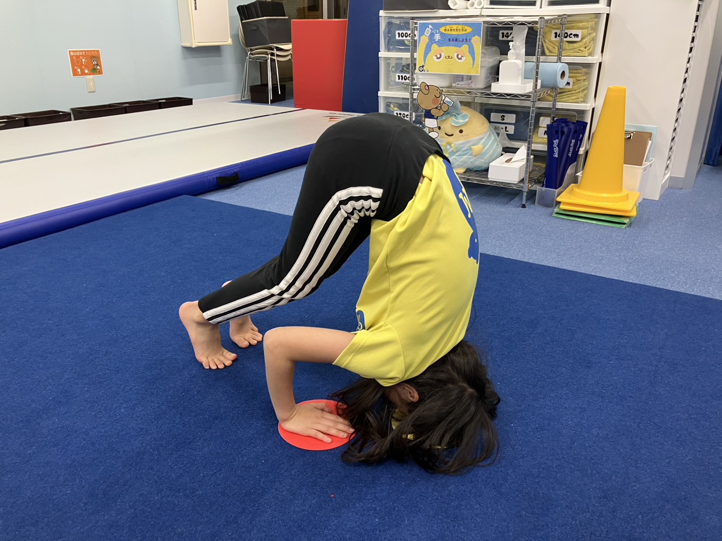 頭はね跳びの手と頭の位置を印に合わせて練習している女の子の様子