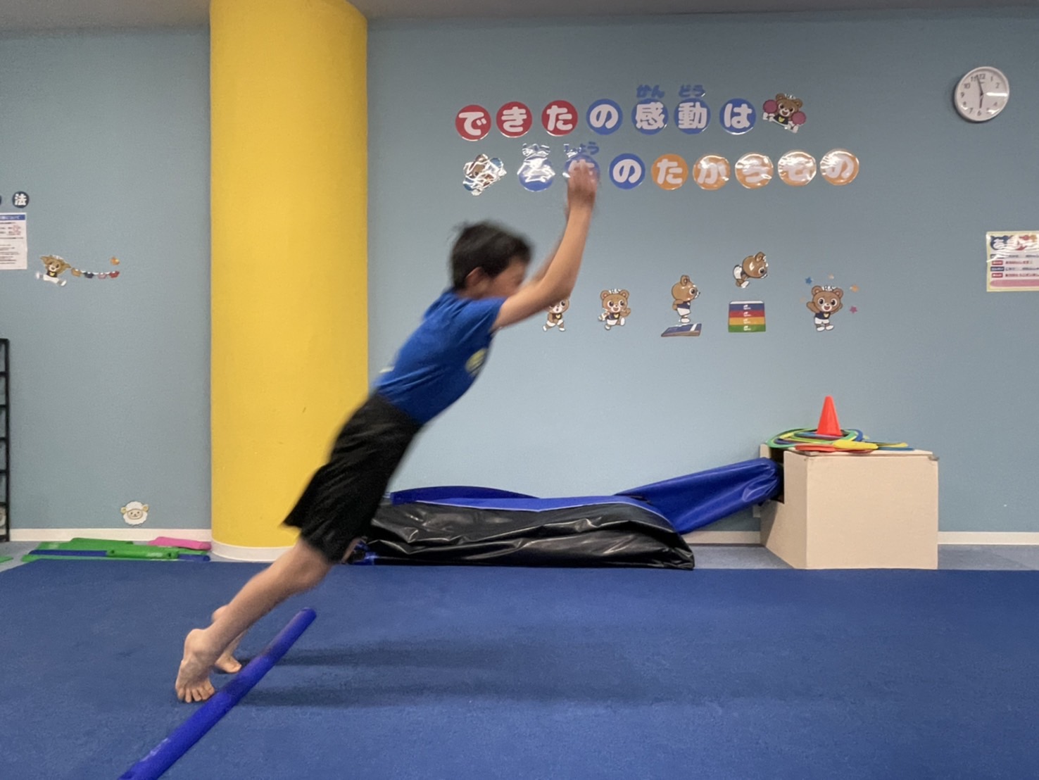 前方に向かって大きく腕を振り、上体を傾けて立ち幅跳びの踏切をしようとしている様子