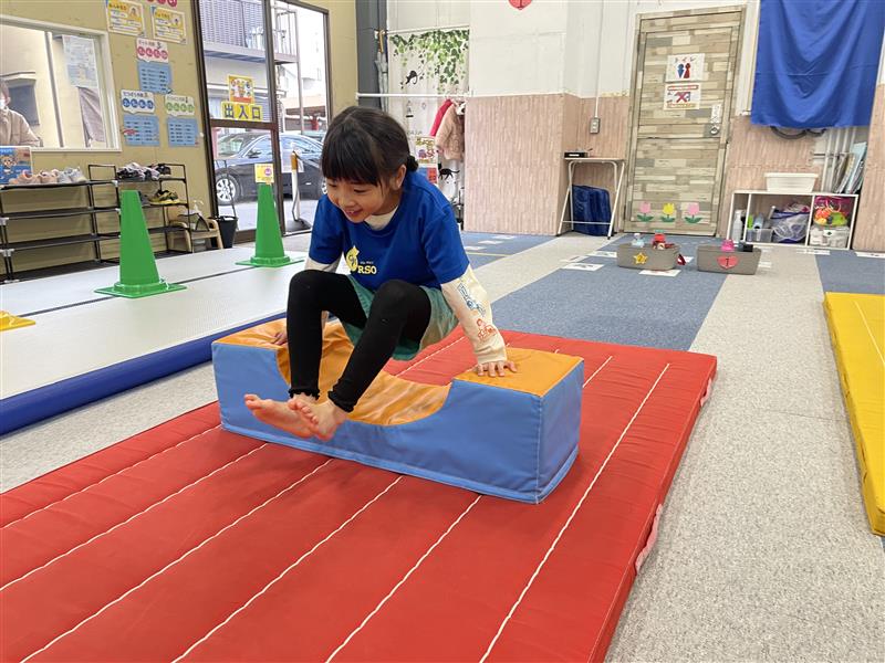 体操教室のボックスを使い、腕の力で地面から足を浮かせる女の子の様子