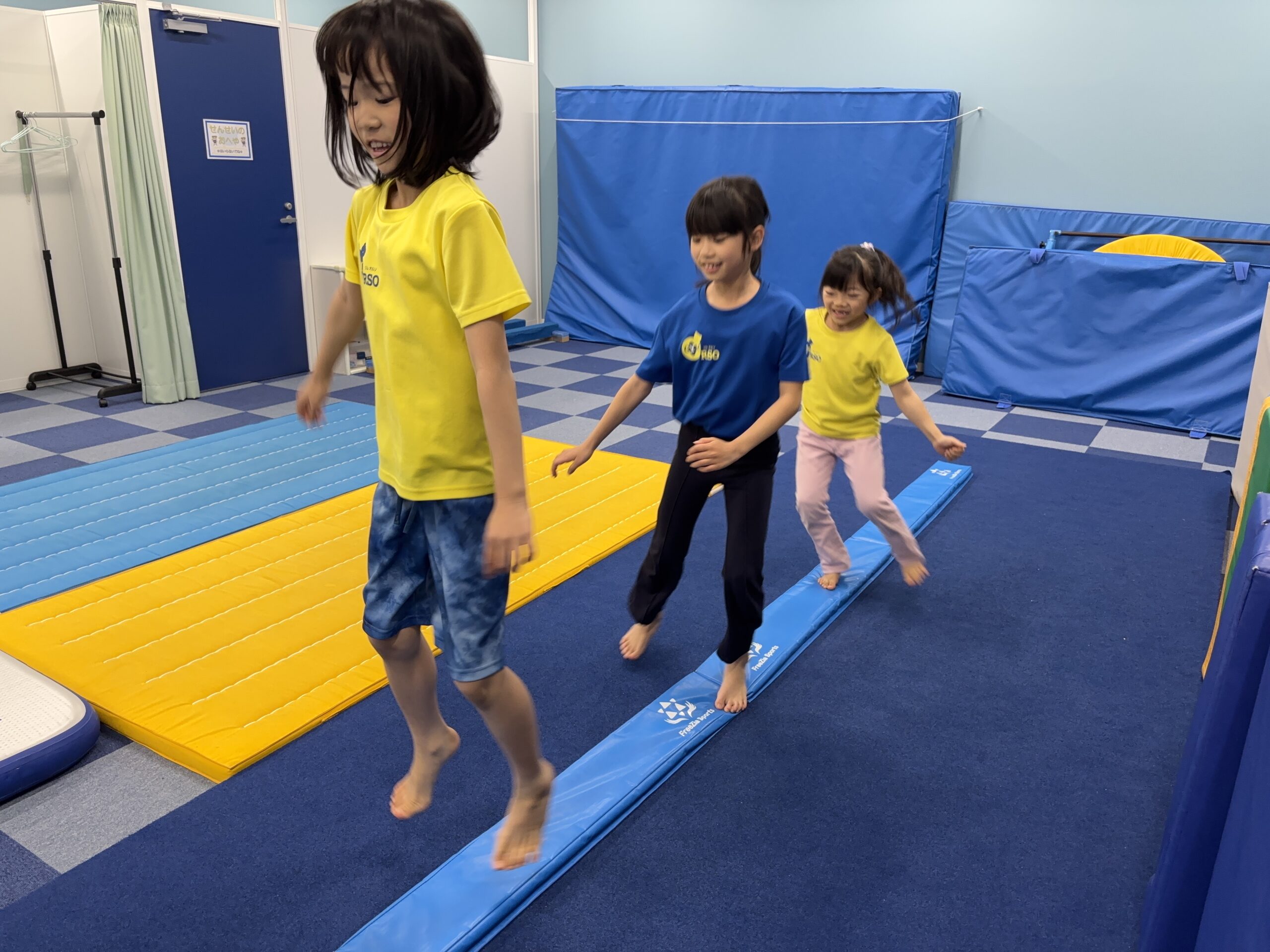 ソフト平均台に片足を乗せサイドステップをする子どもたちの様子