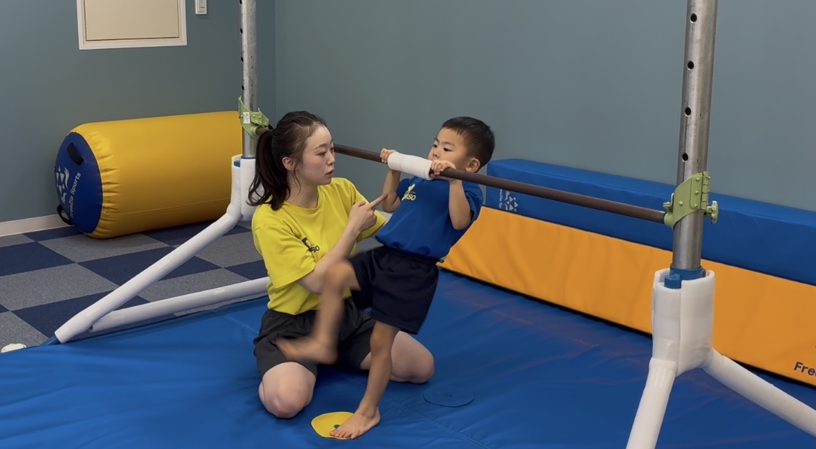 鉄棒に順手でつかまり逆上がりの姿勢に入る子どもの様子