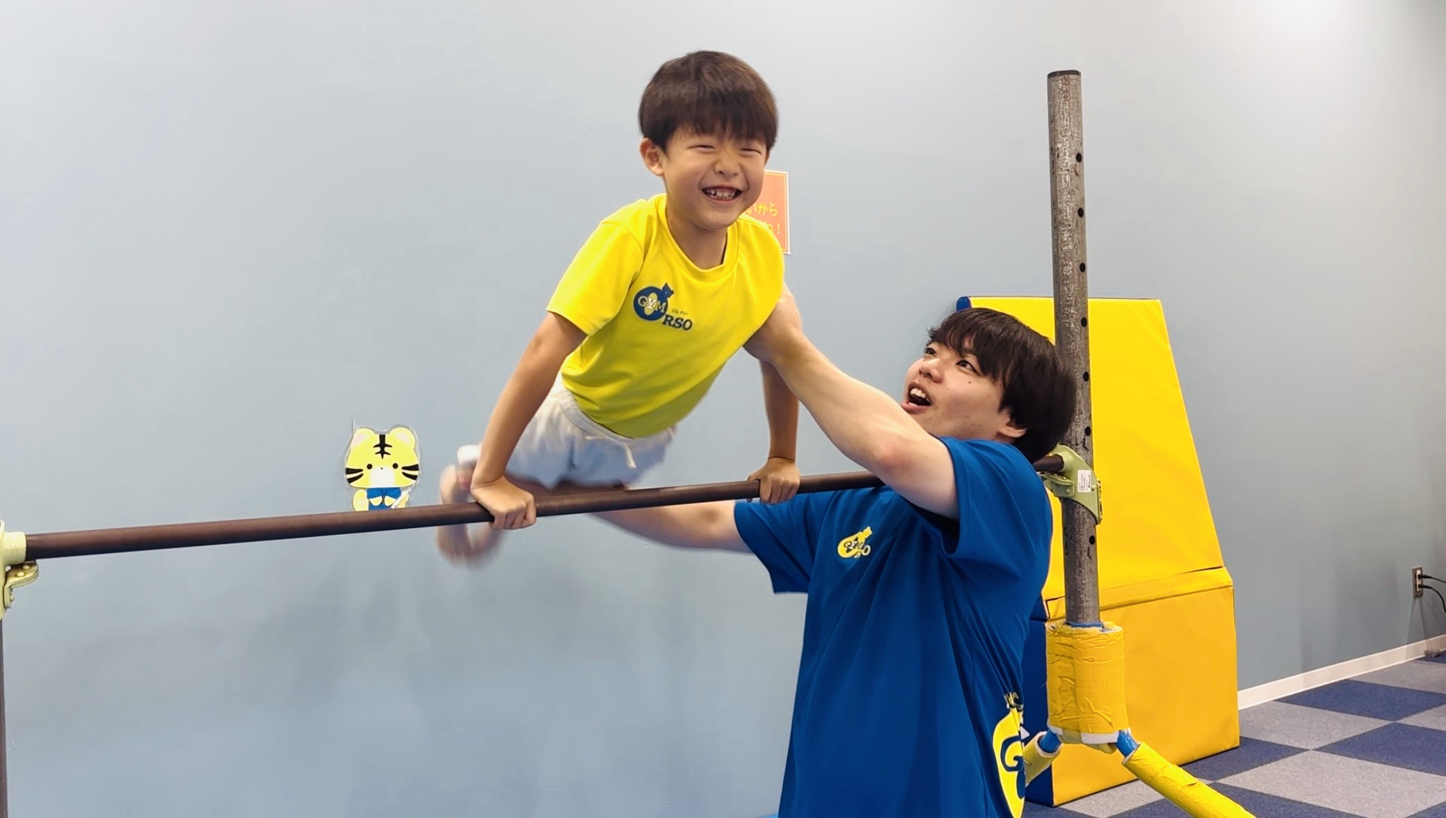 鉄棒の支持姿勢から足を振り上げ空中逆上がりの姿勢に入る子どもの様子